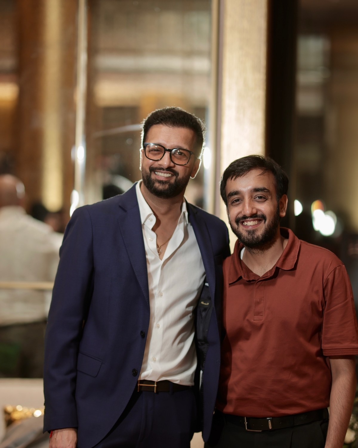 Sahil Jindal in a navy suit with a founder at an evening gathering in a hotel lobby