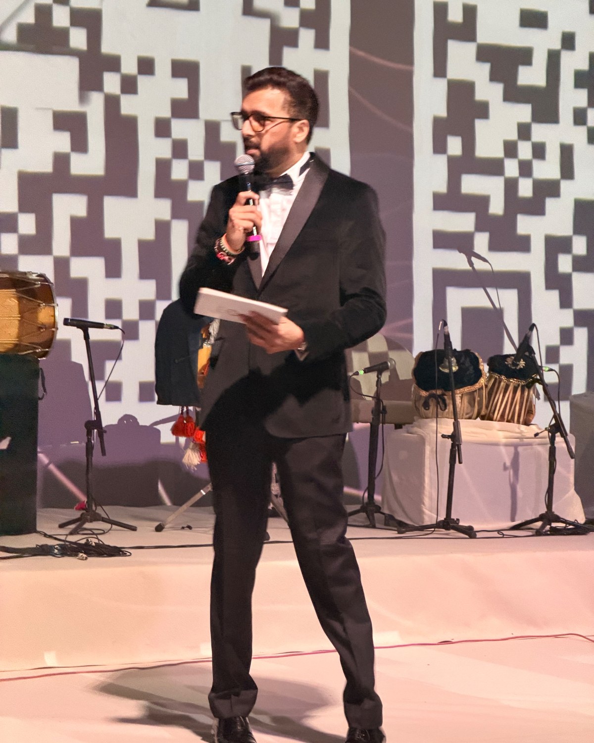 Sahil Jindal hosting an awards evening on stage in a tuxedo