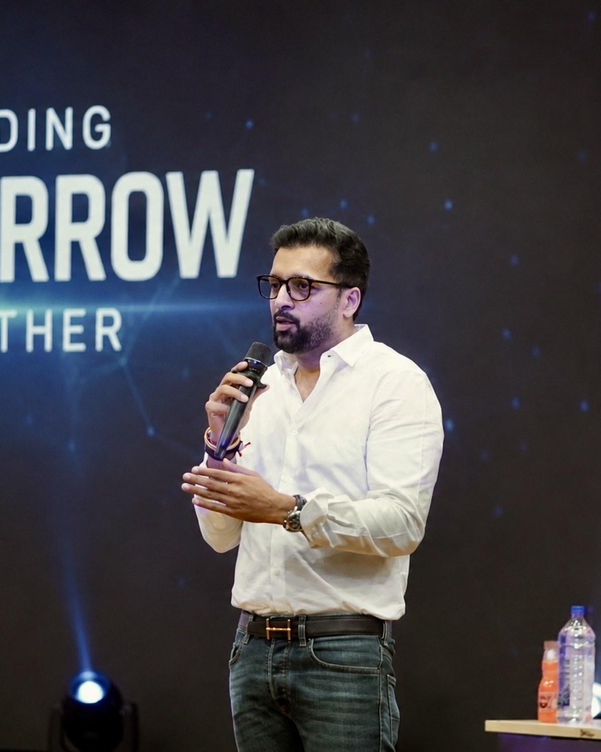 Sahil Jindal delivering a keynote on stage in front of a Building Tomorrow Together screen