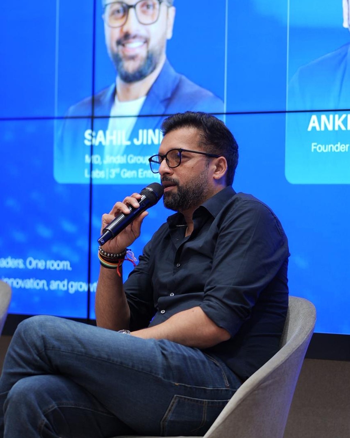 Sahil Jindal speaking on a founders panel with his profile on the screen behind him