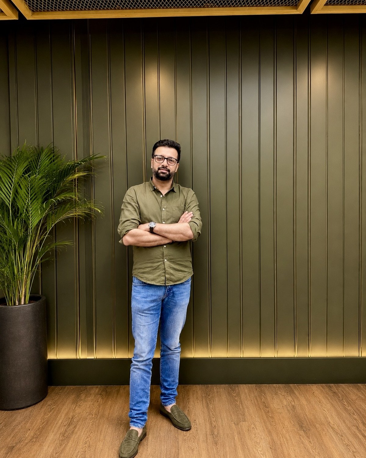 Sahil Jindal in an olive shirt standing against a panelled wall at his Gurugram office